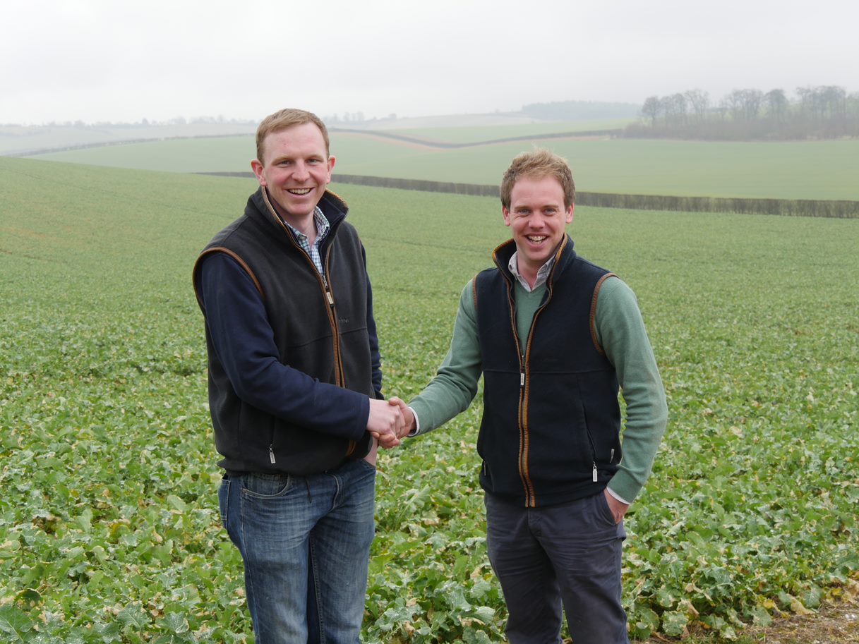 Tom Mead (left) and David Hurst (right) standing in a field and shaking hands